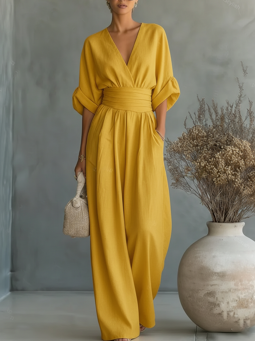 Yellow jumpsuit on a model with a hand in the pocket, posed next to a large pale vase 10