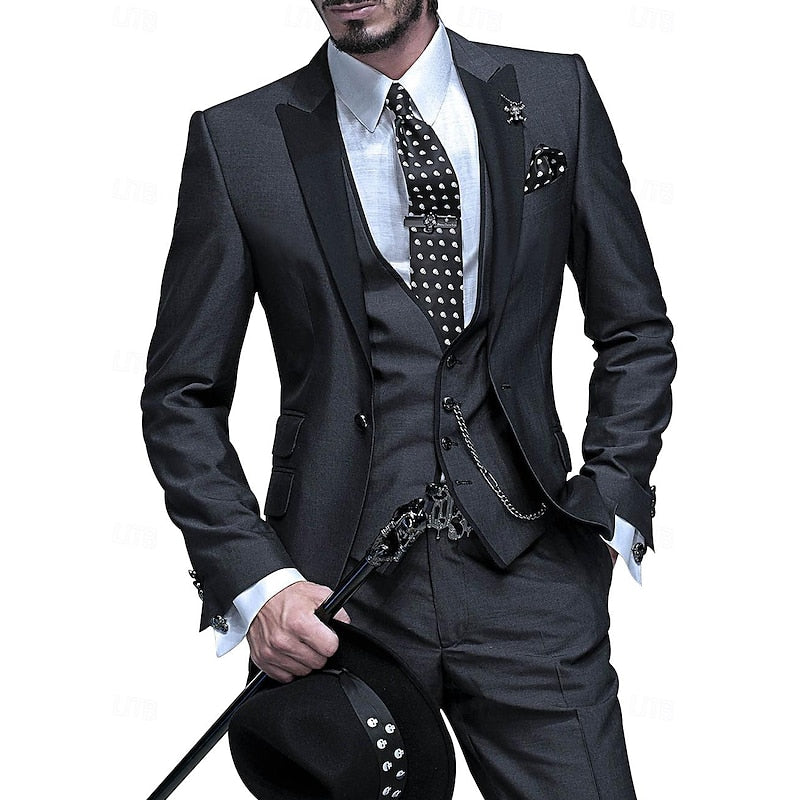 Model in a charcoal three-piece suit with black peak lapels, polka-dot tie and chained waistcoat, holding a black cane and hat. 1
