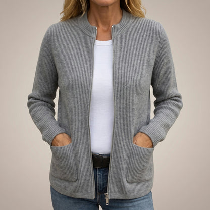 Front view of a grey ribbed-knit cardigan worn open over a white top and jeans, hands tucked into the deep pockets. 1