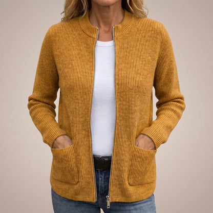 Woman wearing the mustard ribbed knit cardigan unzipped over a white top and jeans, with her hands tucked into the front pockets. 3