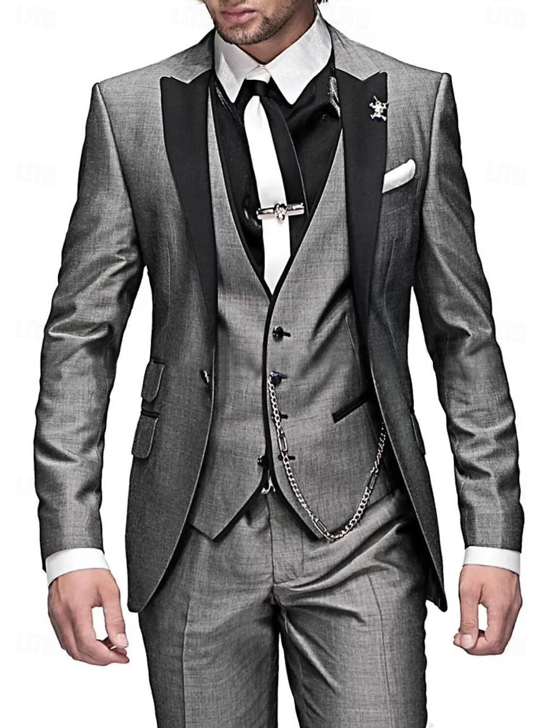 Model in a shimmering grey three-piece suit with black peak lapels, white tie on a black shirt and a silver waistcoat chain. 3