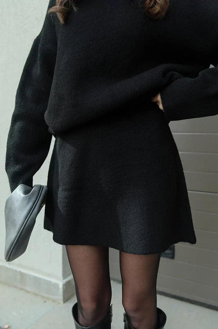 Detail of the black flared mini skirt and sweater hem, worn with sheer tights and boots 7