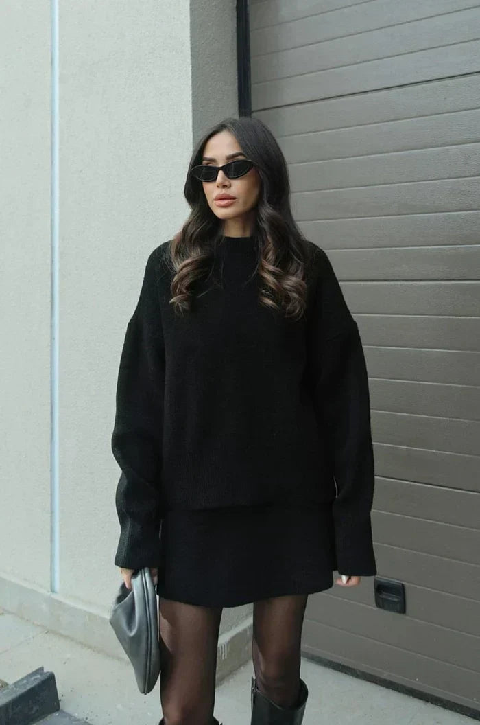 Model in the black set standing beside a garage door, wearing tights and black boots 5