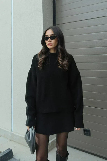 Model in the black set standing beside a garage door, wearing tights and black boots 5