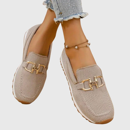Beige mesh slip-on shoes worn crossed, close view of gold buckles and white sole 10