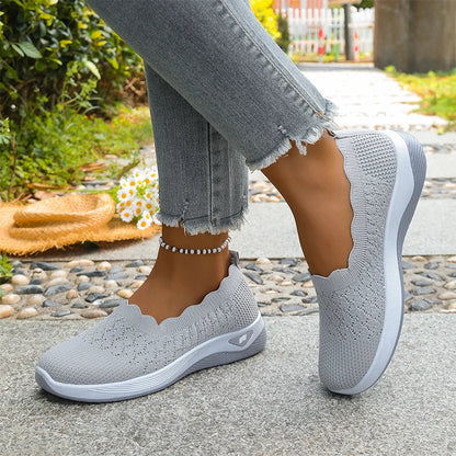 Grey knit slip-on shoes worn on a stone path, with frayed jeans, a beaded anklet and daisies 12