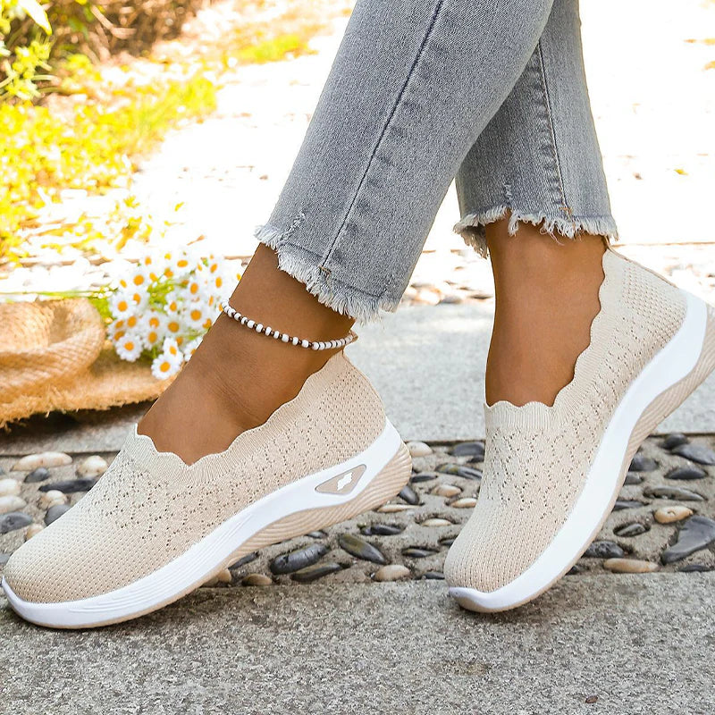Beige knit slip-on shoes worn by a model with frayed jeans and a beaded anklet, daisies nearby 8