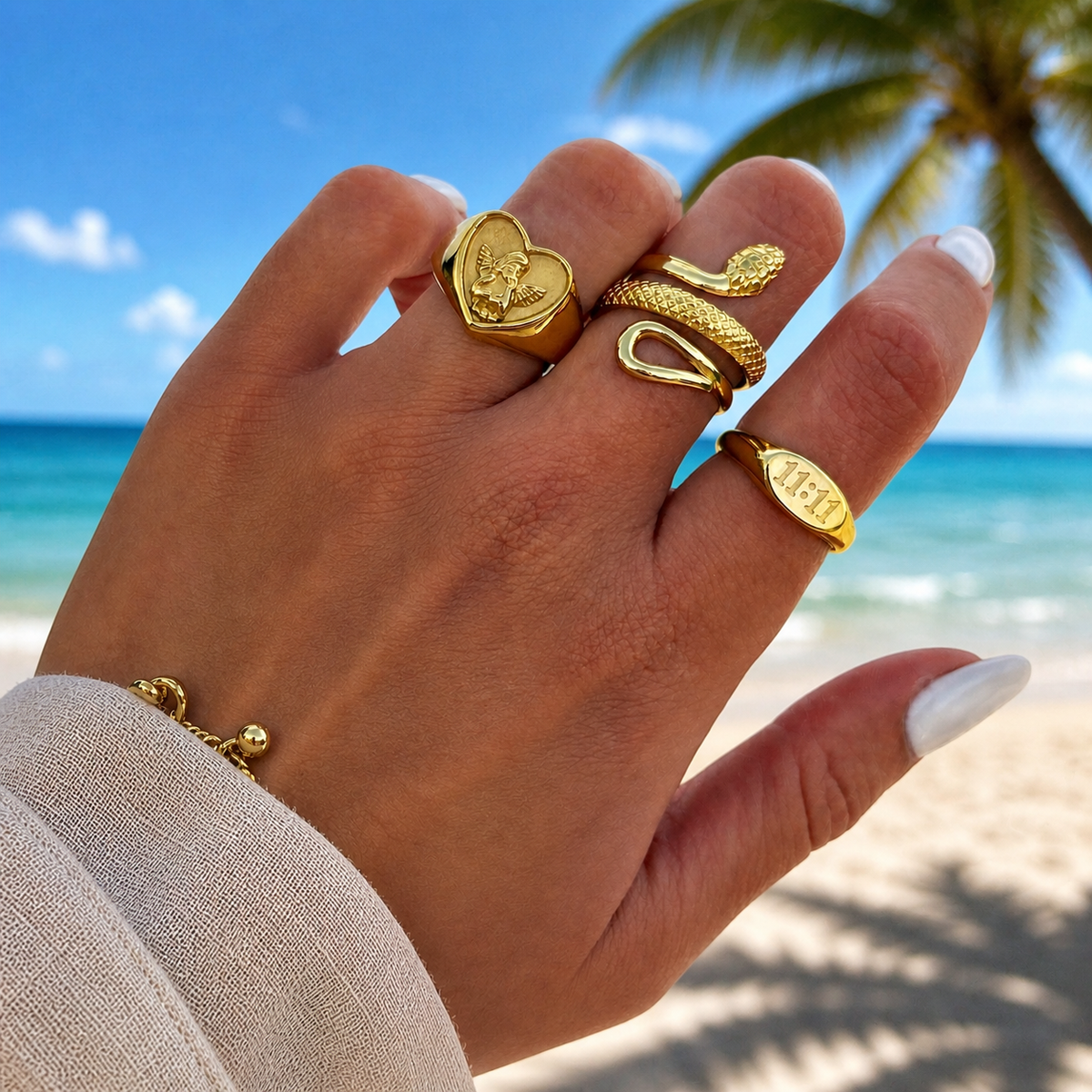 Hand wearing the heart cherub ring alongside a snake ring and an oval ring on a sunny beach 3