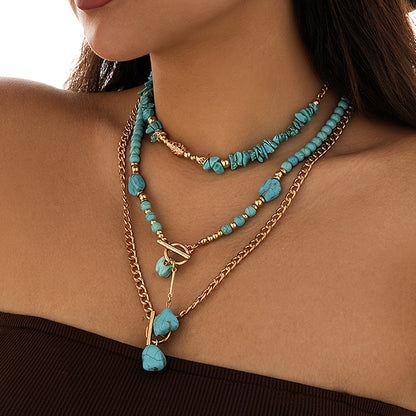 Side-angled view of the three layered necklaces on a model, with a dark brown top behind 2