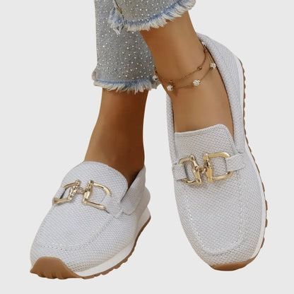 Light grey mesh slip-ons worn crossed, close view of gold buckles and stitched toe 9