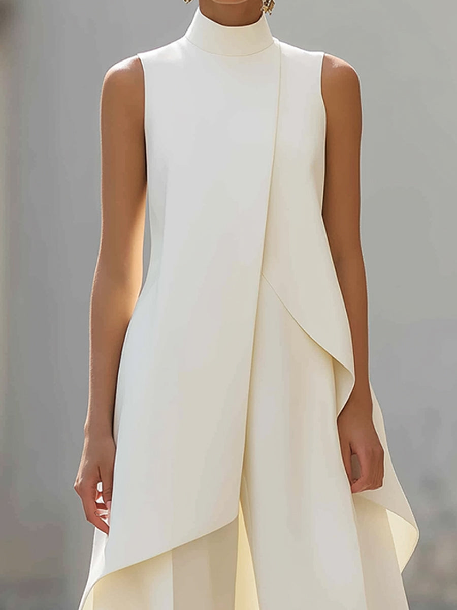 Close-up of the cream top's high neckline, sleeveless cut and diagonal overlap falling into an uneven, curved hem. 11