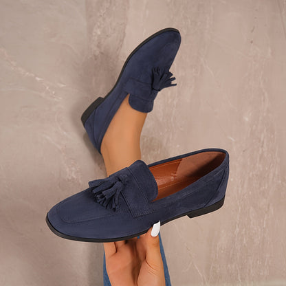 Navy loafers held up in a hand against a stone wall, showing the lining 17