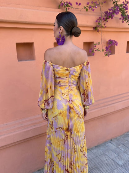 Back view of the off-shoulder dress showing the pleated bodice, centre zip and fan-pleated skirt flowing from the waist. 3