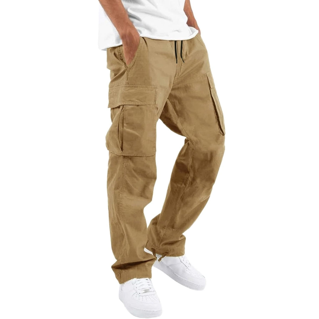 Model wearing sand-coloured cargo trousers with drawstring waist and flap pockets, hands in pockets, with white t-shirt and trainers. 7