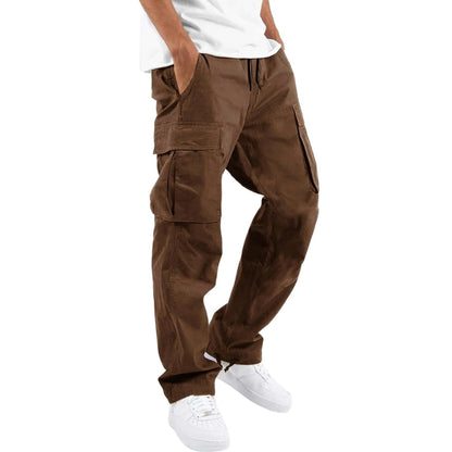 Model wearing brown cargo trousers with drawstring waist and large side flap pockets, paired with a white t-shirt and trainers. 5