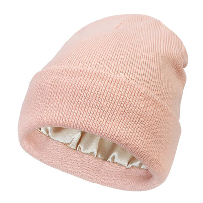 Pale pink ribbed knit beanie with folded cuff, revealing the cream satin lining inside 4