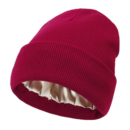 Deep red ribbed knit beanie with folded cuff, the champagne satin lining visible inside 9