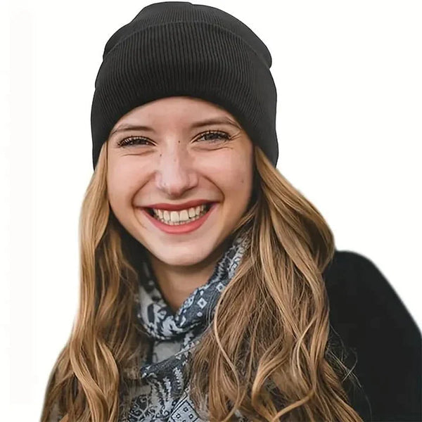 Smiling woman with long wavy hair wearing a black knit beanie and patterned scarf 3