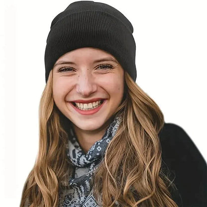 Smiling woman with long wavy hair wearing a black knit beanie and patterned scarf 3