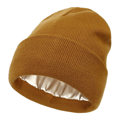 Mustard-brown ribbed knit beanie with turned-up cuff, showing the smooth satin lining inside 1