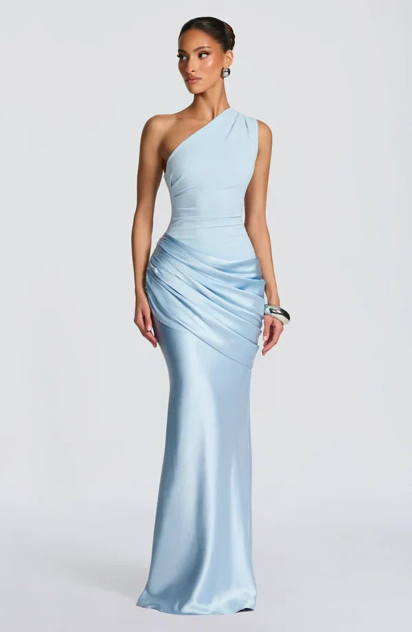 Pale blue one-shoulder maxi dress with a draped satin hip panel, worn by a model glancing to the side. 1