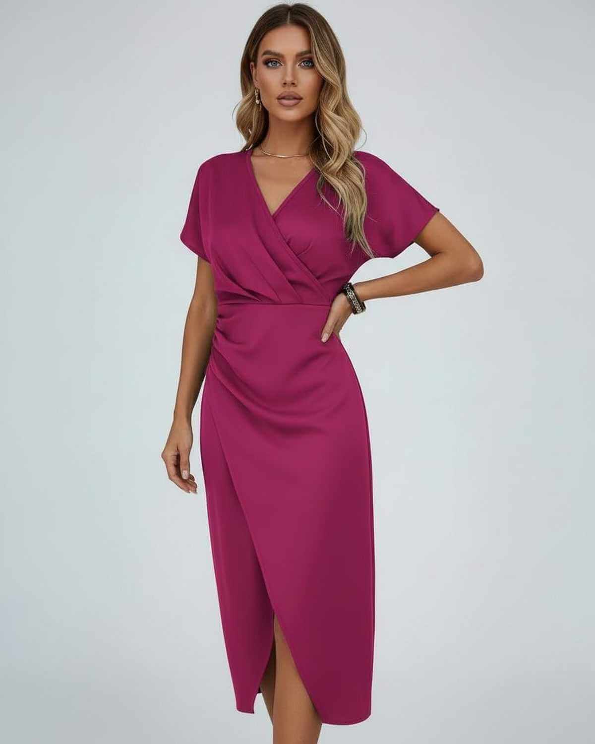 Model wearing the short-sleeved wrap dress in magenta, one hand on her hip 1