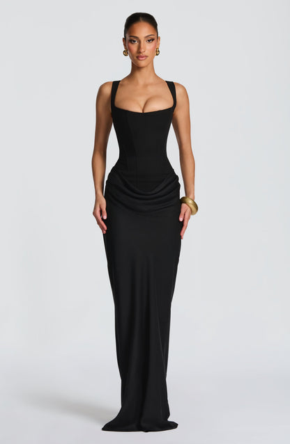 Model facing forward in the black corset maxi dress with draped hip detail, gold hoop earrings and a gold bangle. 12