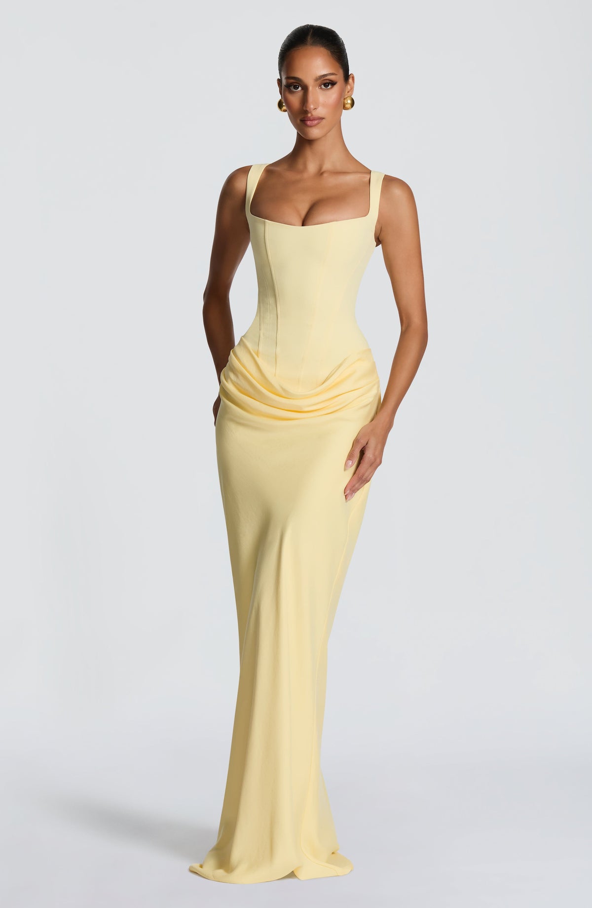 Pale yellow maxi dress with one hand on the hip, showing the ruched drape and flowing long skirt 10
