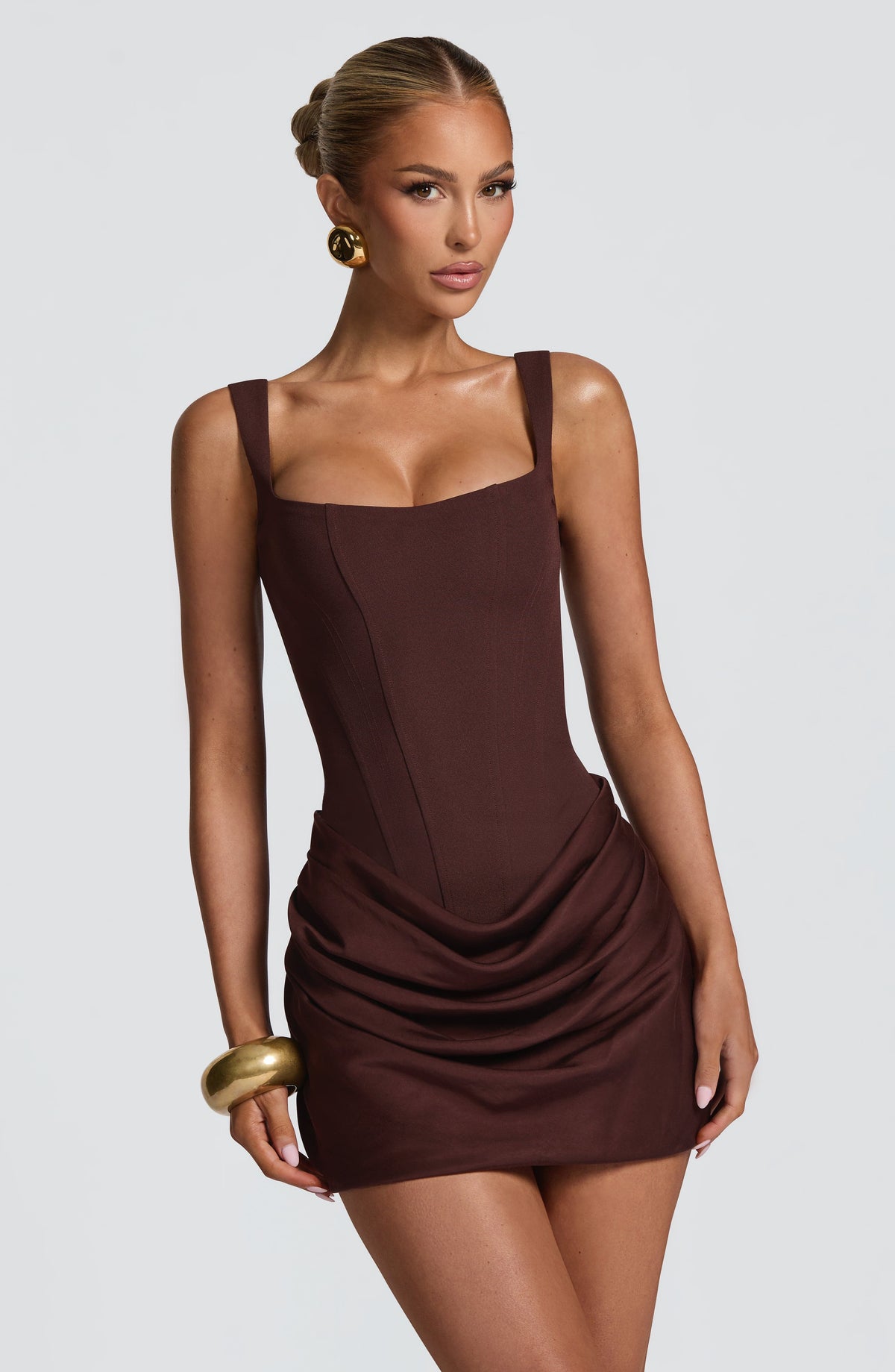 Close-up of the brown dress from the front, with a gold bangle and the ruched, draped skirt. 4