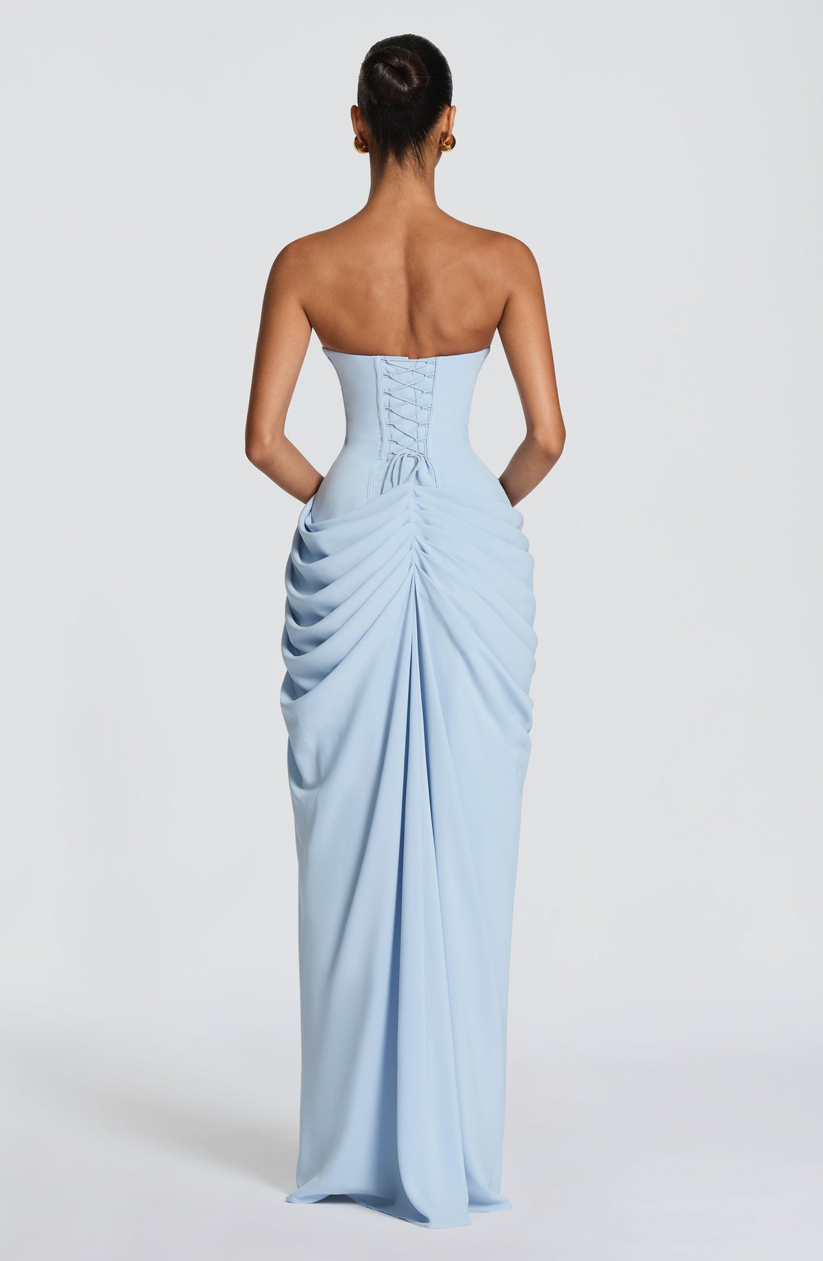 Back view of the pale blue dress showing the lace-up corset back and gathered, ruched skirt draping to the floor. 22
