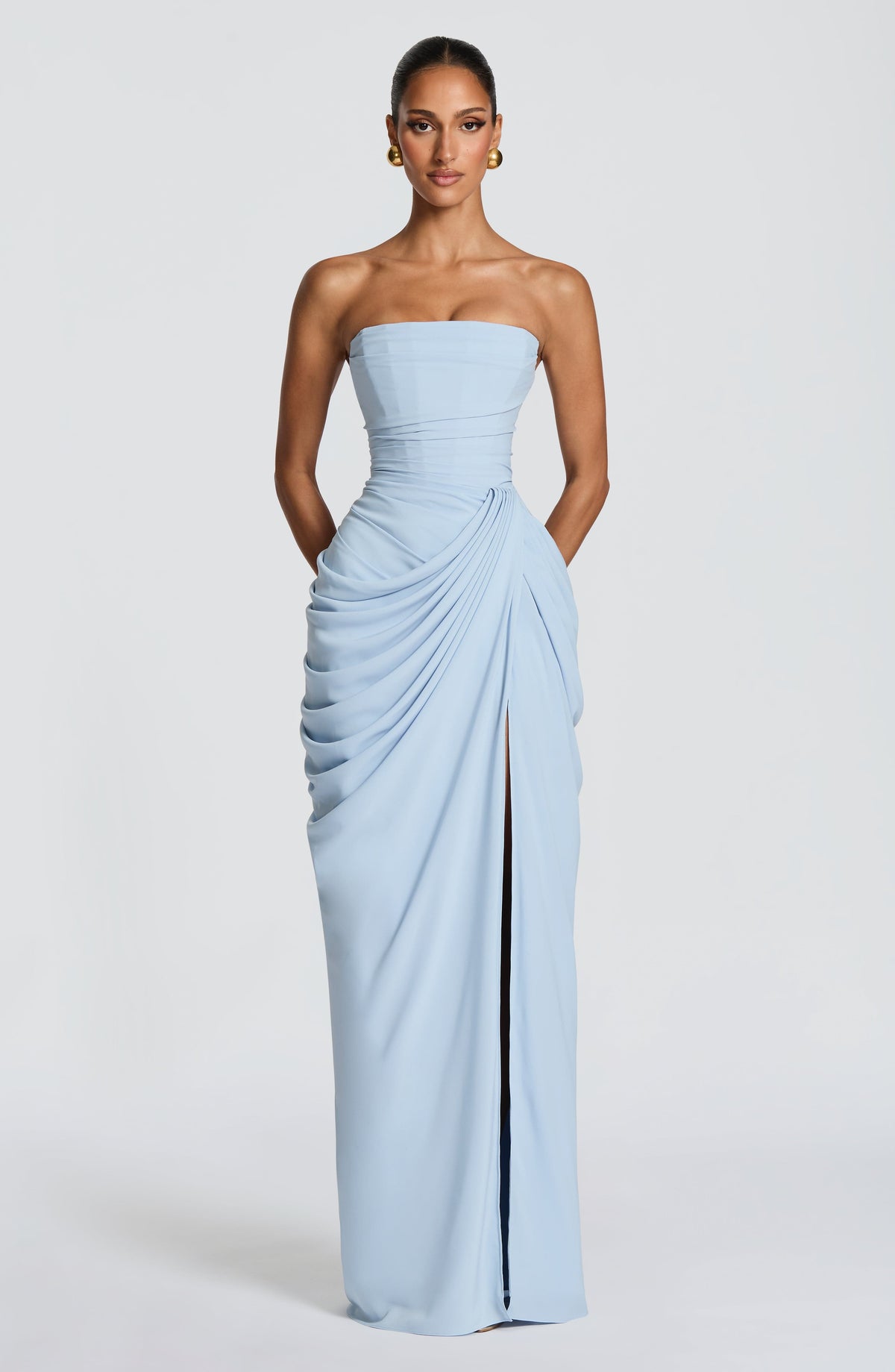 Front view of the pale blue dress on a model with hands in the side pockets, slit slightly open. 23