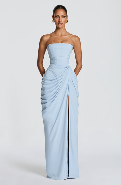 Front view of the pale blue dress on a model with hands in the side pockets, slit slightly open. 23
