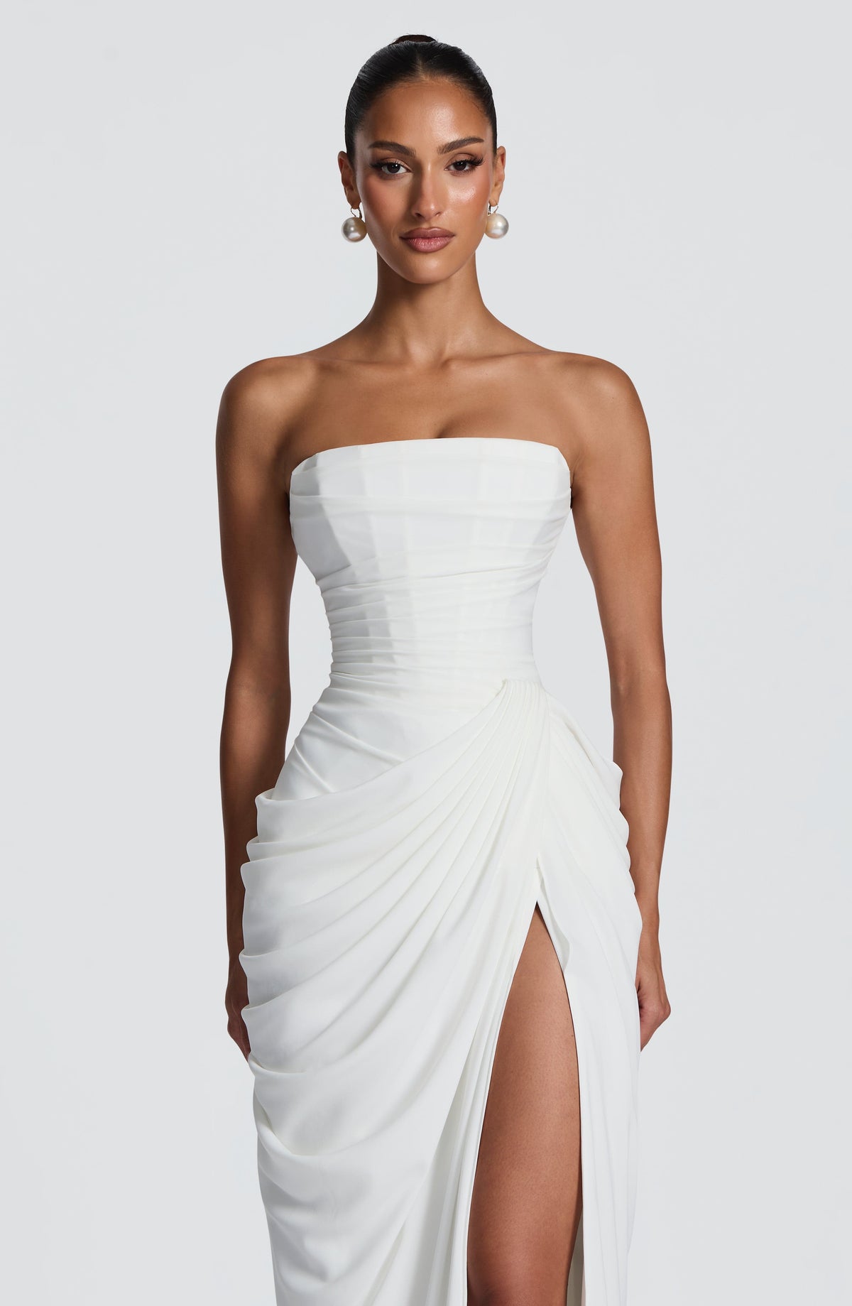 Close-up of the white dress from head to thigh, showing the pleated corset bodice, pearl drop earrings and gathered side drape. 8