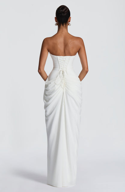 Back view of the white strapless dress showing the lace-up corset back with ties and ruched drape down the skirt. 10