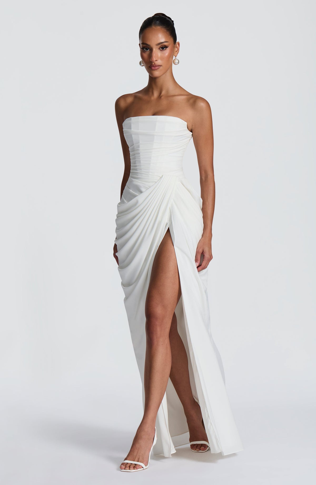 Angled front view of the white strapless maxi dress, showing the draped skirt falling open at the high thigh slit. 9