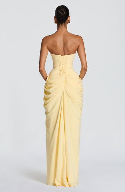 Back view of the pale yellow strapless dress showing the lace-up corset back and gathered, ruched drape down the skirt. 2