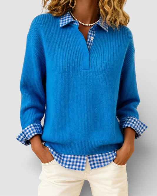 Blue ribbed jumper with a gingham shirt collar and cuffs, worn by a model with hands in the pockets of cream trousers. 1