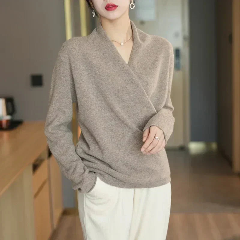 Model standing in taupe wrap jumper with white trousers, one hand resting on her stomach 7