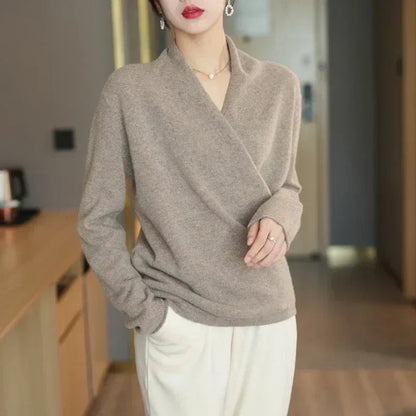 Model standing in taupe wrap jumper with white trousers, one hand resting on her stomach 7