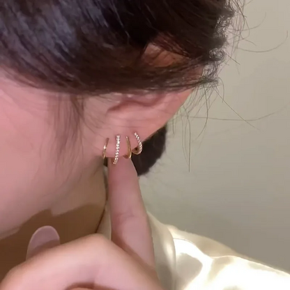 Side view of a four-claw earring in the ear, with a fingertip pointing at the sparkling bands 3