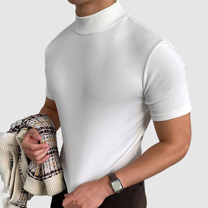 Close three-quarter view of the white mock-neck tee on a model holding a patterned knit jacket, with a wristwatch visible. 7