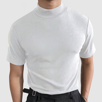 Front view on a model of the white short-sleeved mock-neck tee, worn with dark trousers and a black belt. 2
