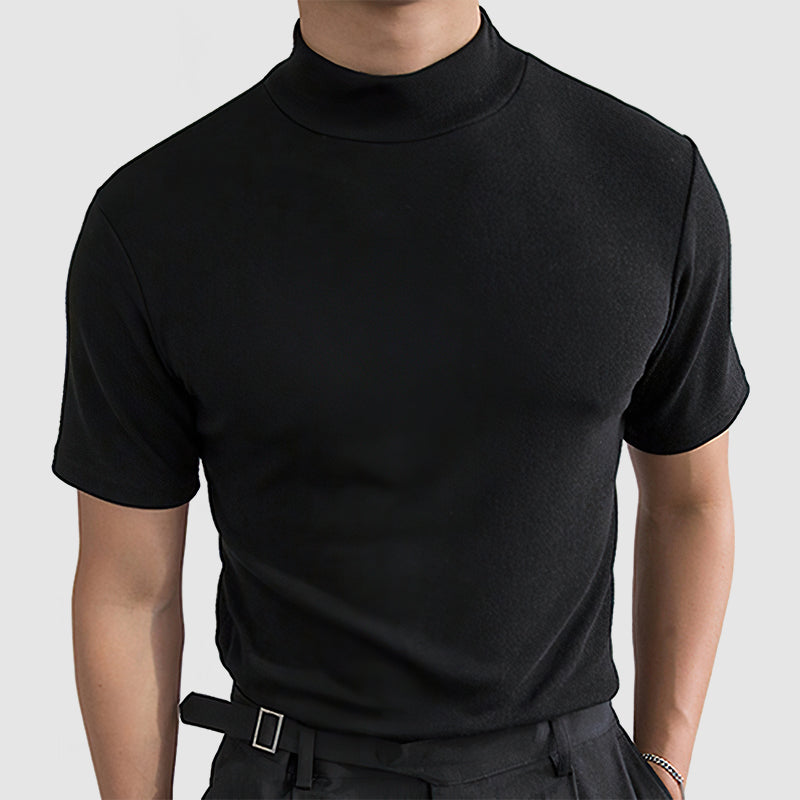 Front view on a model of the black short-sleeved mock-neck tee, worn tucked into dark trousers with a buckled belt. 1