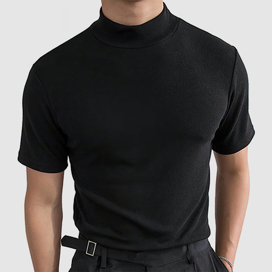 Front view on a model of the black short-sleeved mock-neck tee, worn tucked into dark trousers with a buckled belt. 1