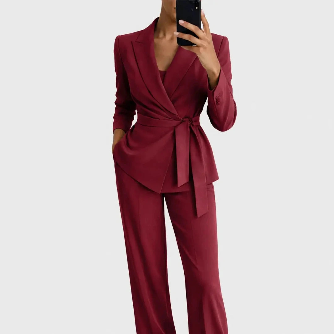 Model wearing the burgundy version of the belted wrap blazer and wide-leg trousers, posed with a phone in hand. 5