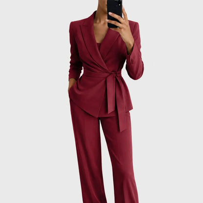 Model wearing the burgundy version of the belted wrap blazer and wide-leg trousers, posed with a phone in hand. 5