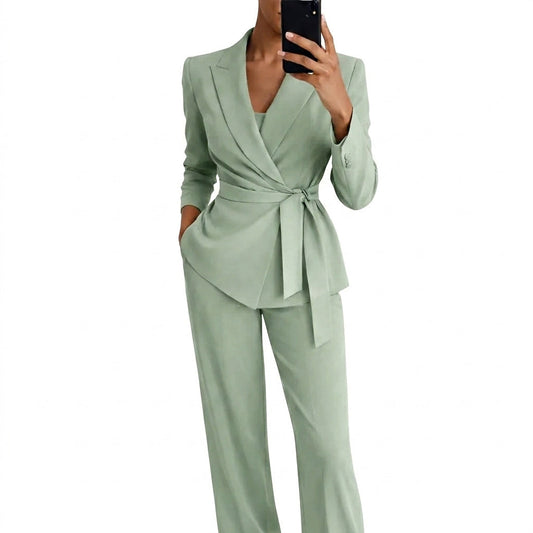 Model in the sage green wrap-front blazer with tie belt and wide-leg trousers, holding a phone and one hand in a pocket. 1