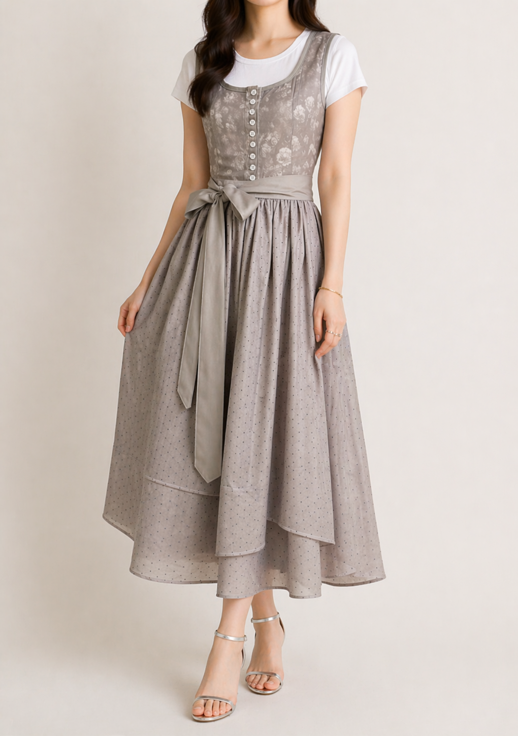 Model wearing the grey dirndl with a white t-shirt, bow at the waist and a full dotted tiered midi skirt, shown slightly angled. 2