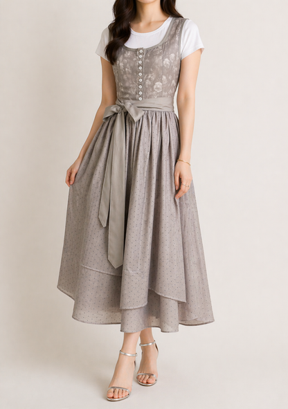 Model wearing the grey dirndl with a white t-shirt, bow at the waist and a full dotted tiered midi skirt, shown slightly angled. 2