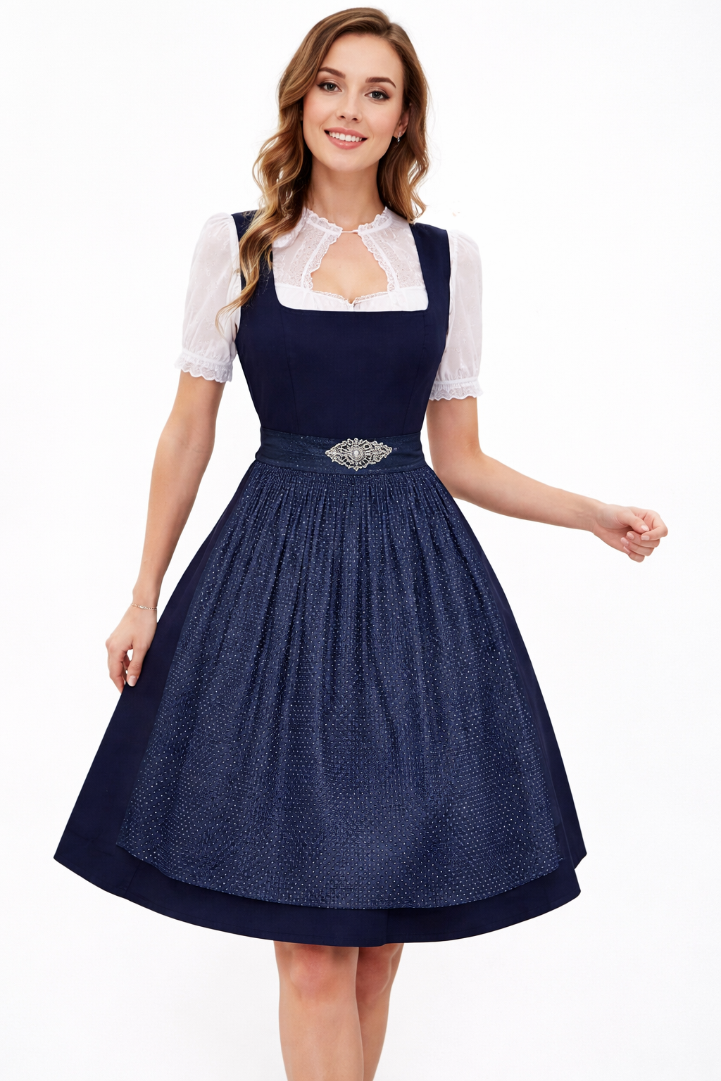 Smiling model in a navy dirndl with dotted textured apron, ornate brooch and white blouse with lace keyhole neckline and short puff sleeves. 3